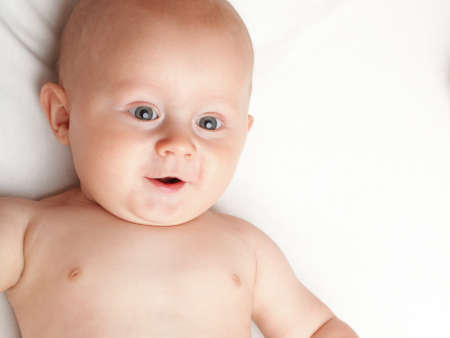 baby boy in diaper on white, blue eyeの写真素材