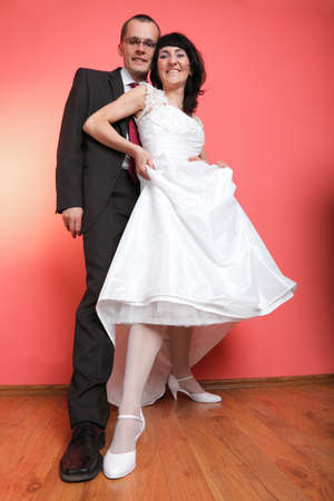 Happy smiling bride and groom on red backgroundの写真素材