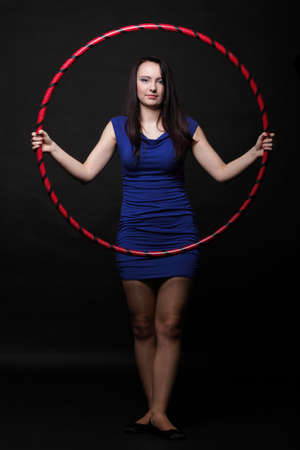 Beautiful woman in a sport wear. Dance hoop gym exercises black backgroundの写真素材