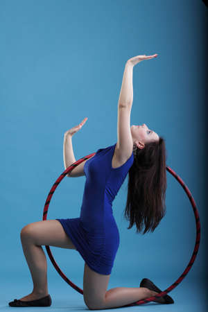 Beautiful woman in a sport wear. Dance hoop gym exercises blue backgroundの写真素材