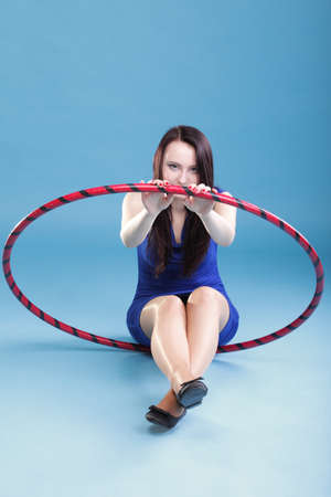 Beautiful woman in a sport wear. Dance hoop gym exercises blue backgroundの写真素材