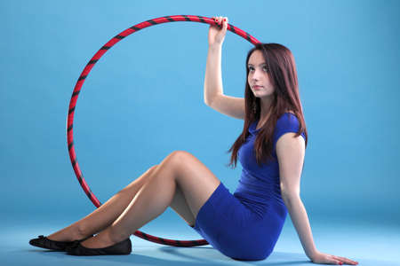 Beautiful woman in a sport wear. Dance hoop gym exercises blue backgroundの写真素材