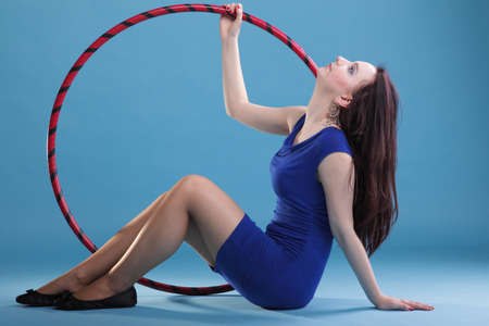 Beautiful woman in a sport wear. Dance hoop gym exercises blue backgroundの写真素材