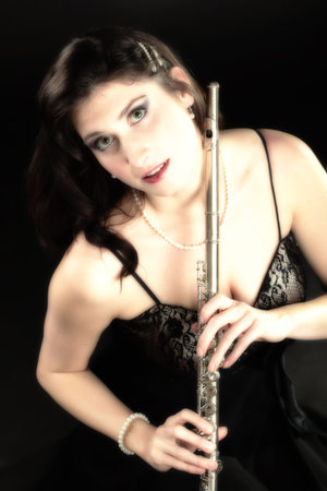 girl woman plays the flute on a black backgroundの写真素材