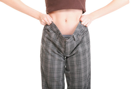 Woman showing how much weight she lost. Healthy lifestyles concept isolatedの写真素材