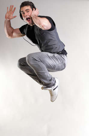 Young man jumping and listening music isolated over a gray backgroundの写真素材