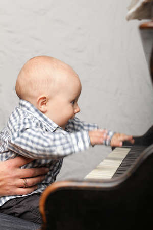 beautiful little baby boy learning plays pianoの写真素材