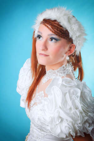 Beautiful ginger in white dress of Snow Queen blue backgroundの写真素材