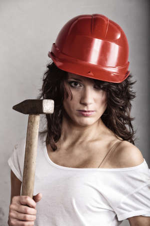 Sex equality and feminism. Sexy girl in safety helmet holding hammer tool. Attractive woman working as construction worker.の写真素材