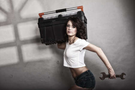Sex equality and feminism. Sexy girl holding toolbox and wrench spanner tool. Attractive woman working as repairman or mechanicの写真素材