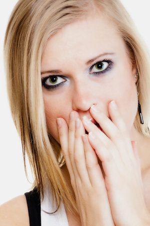 Body language and emotions. Surprised afraid blonde girl shocked young woman covering mouth with...