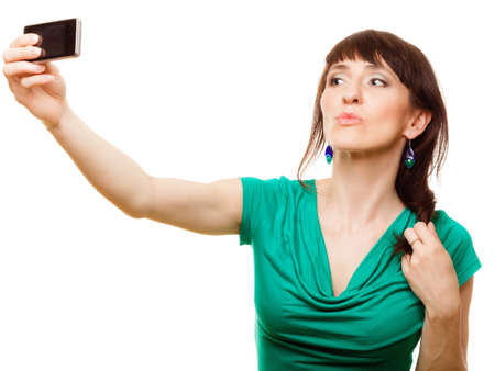 Technology and internet concept - smiling woman taking self picture with smartphone camera isolatedの写真素材