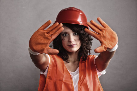 Sex equality and feminism. Sexy girl construction worker builder in orange vest and hard hat showing stop sign hand gesture.の写真素材