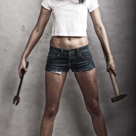 Sex equality and feminism. Sexy girl holding hammer and wrench spanner tools. Attractive woman working as repairman.の写真素材