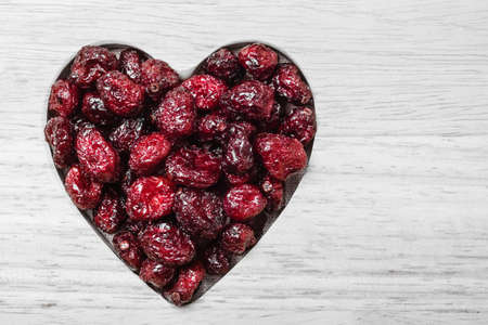 Healthy high fiber food, organic nutrition. Dried cranberries cranberry fruit in shape of heart on wooden surface backgroundの写真素材