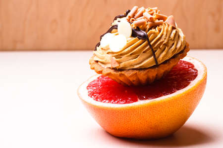 Concept of making choice: healthy low-calorie or unhealthy high-calorie food, slimming or fattening. Grapefruit and cake cupcake.の写真素材