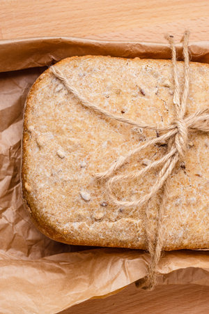 Food. Closeup freshly baked loaf of bread on baking paper top view