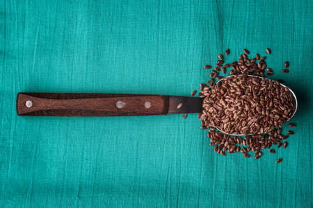 Healthy food. Flax seeds linseed on kitchen spoon linen green color backgroundの写真素材