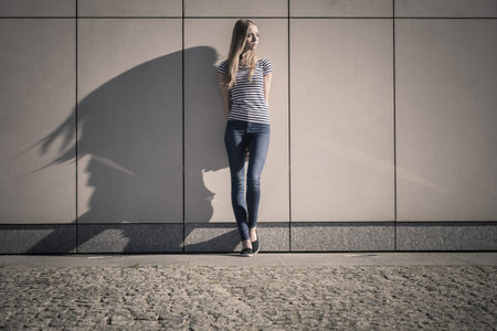 Young blonde woman in full length casual style against stone grunge wallの写真素材