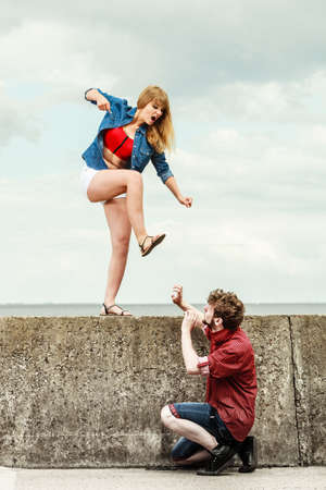 Relationship concept. Woman and man young couple in love playing fighting, angry fury girlfriend screaming outdoor on sky backgroundの写真素材