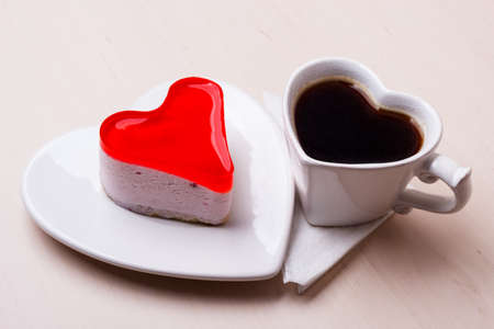 Heart shaped coffee cup and jelly cake on wooden kitchen table.の写真素材