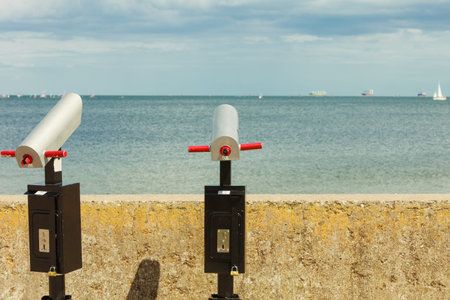 Watching sea or ocean water trought binoculars telescope on pier. Travel and tourism.