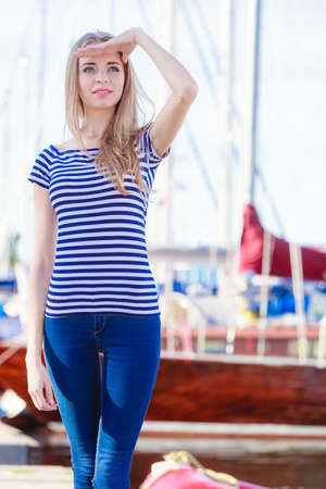 Travel tourism and people concept. Fashion blonde girl in marina against yachts in portの写真素材