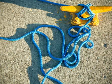 Yellow mooring bollard with blue rope in marina closeupの写真素材