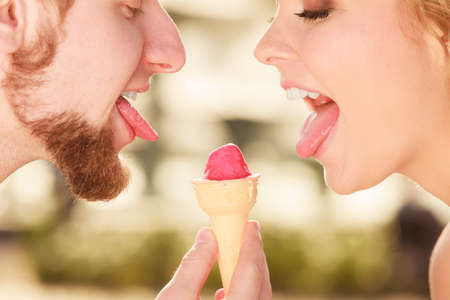 Summer holidays and happiness concept. Young couple eating ice cream outdoor in the cityの写真素材