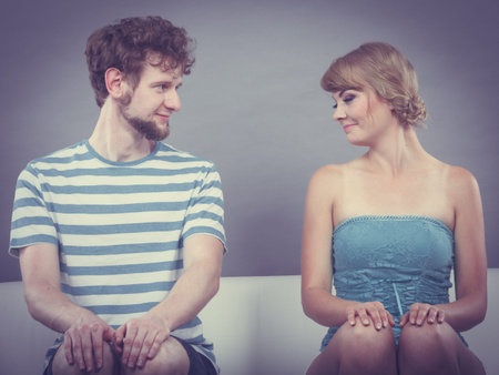 Relationship concept. Shy woman and man sitting close to each other on the couch.