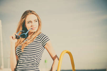 Summer relaxation concept.. Portrait girl with blue heart shaped sunglasses enjoying summer breeze outdoor on sky backgroundの写真素材