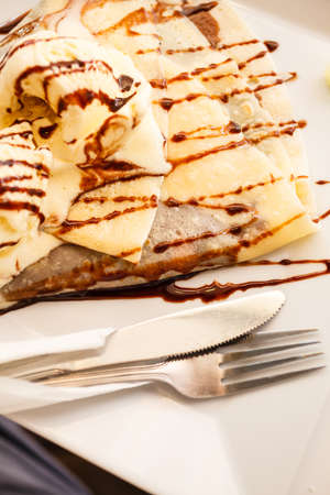 Pancake with ice cream and chocolate sauce on tableの写真素材