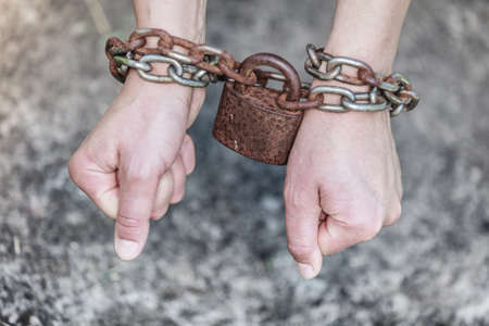 Crime, arrest jail concept. Closeup woman with chained hands and padlock on grunge backgroundの写真素材