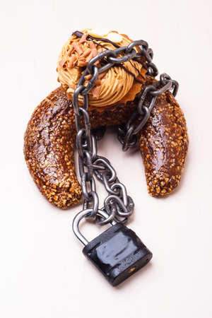 Diet sugar sweet food addiction concept. Cake cupcake wrapped in metal chain and padlockの写真素材