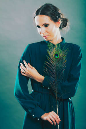portrait of beautiful woman holding peacock featherの写真素材