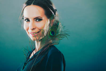 portrait of beautiful woman holding peacock featherの写真素材