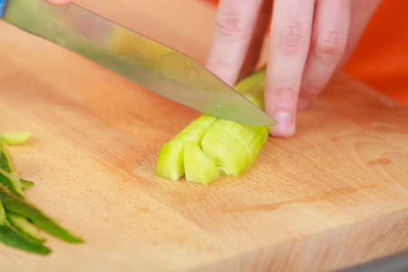 Healthy eating, vegetarian food, cooking, dieting and people concept. Closeup man hands in kitchen at home preparing fresh salad slicing vegetables green cucumber on cutting boardの写真素材