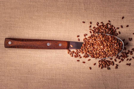 Healthy food. Flax seeds linseed on kitchen spoon burlap sack backgroundの写真素材