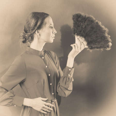 Vintage woman retro style with black feather fan sepia toneの写真素材