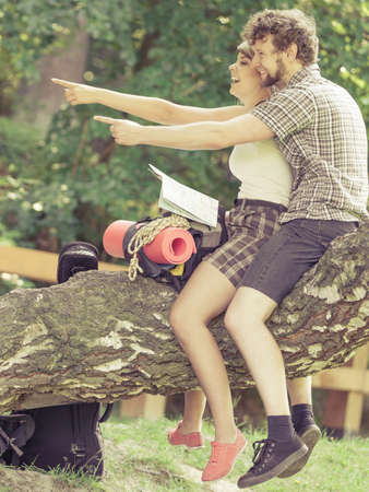 Man and woman tourists backpackers reading map on trip while resting.  Young couple hikers searching looking for direction guide. Backpacking summer vacation travel.の写真素材
