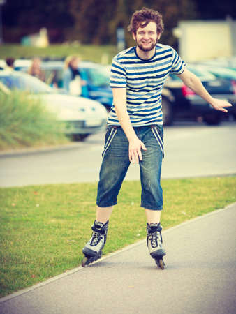 Holidays, active lifestyle freedom concept. Young fit man on roller skates riding outdoors on street, guy rollerblading on sunny dayの写真素材