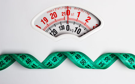 Dieting weightloss slim down concept. Closeup measuring tape on white weight scale copy space text...