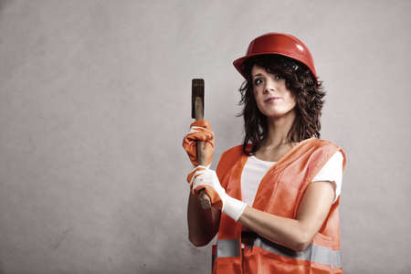 Sex equality and feminism. Sexy girl in safety helmet orange vest holding hammer tool. Attractive woman working as construction worker.の写真素材