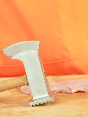 Food preparing, cooking concept. steak chicken breast with meat tenderizer on wooden board close up
