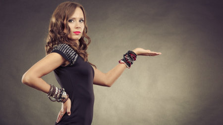 Fashion and advertising concept. Pretty young woman wearing bracelets jewellery in black elegant...