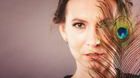 portrait of beautiful woman holding peacock featherの写真素材