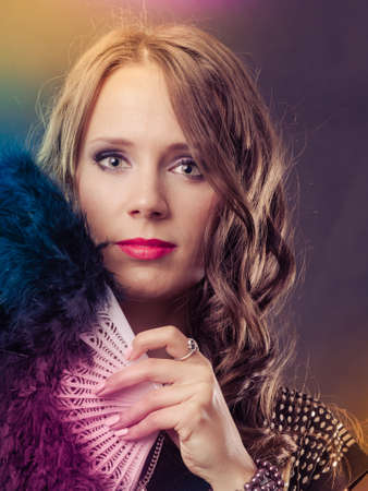 Portrait of beautiful brunette woman with black feather fan in hand on festive colorful backgroundの写真素材