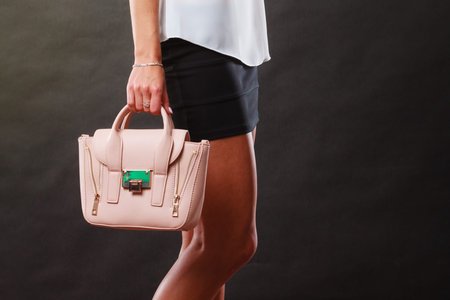 Elegant outfit. Female fashion. Girl in fashionable clothes holding bag handbag on darkの写真素材