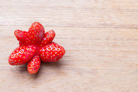 Healthy nutrition diet food modification. Red odd single strawberry fruit on wooden table board copy space text areaの写真素材
