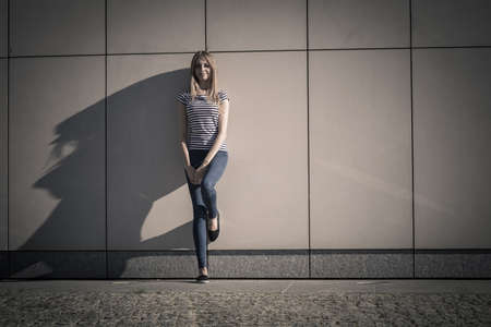 Young blonde woman in full length casual style against stone grunge wallの写真素材